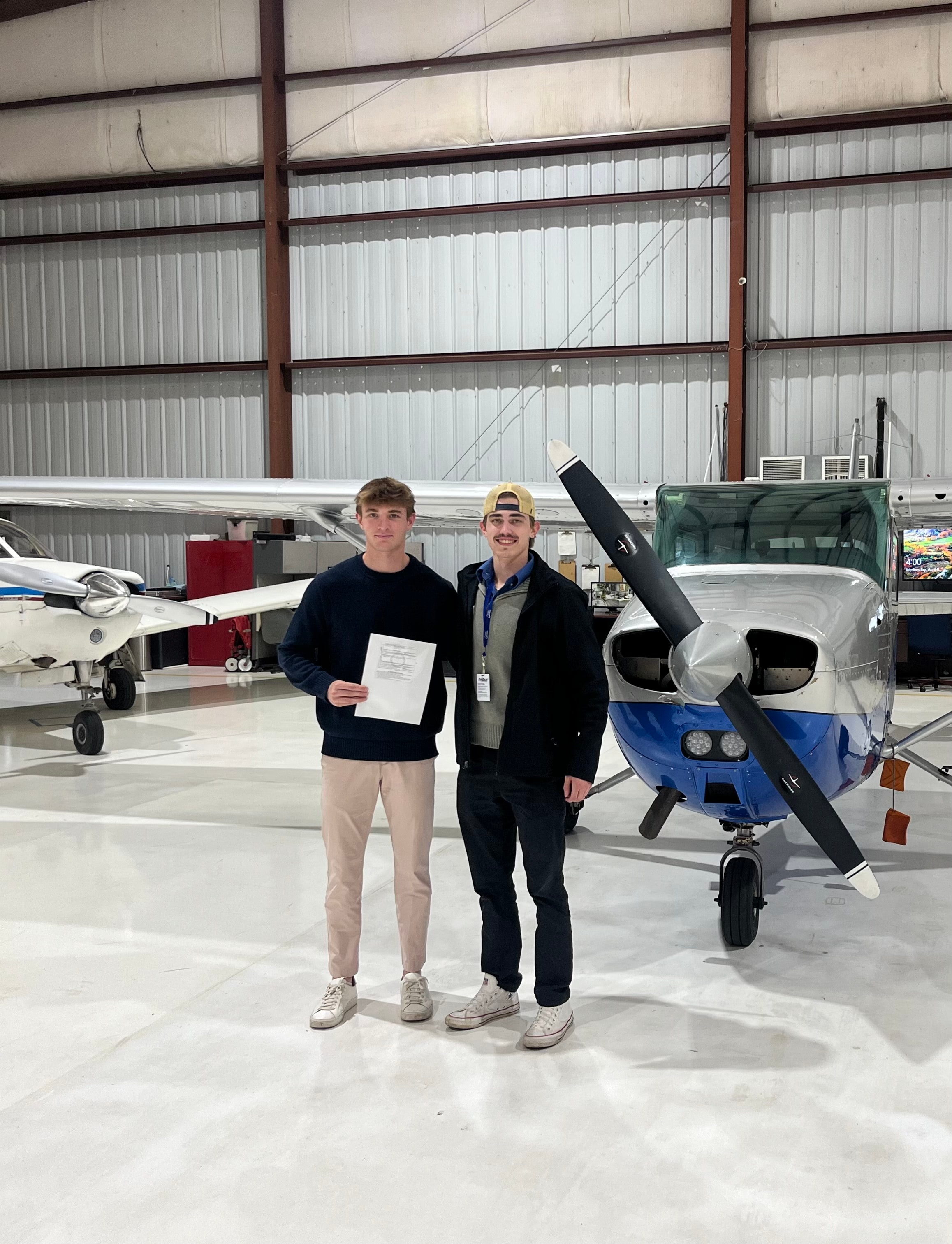 Mark Rolfes with a student pilot in the hangar beside a Cessna training aircraft.